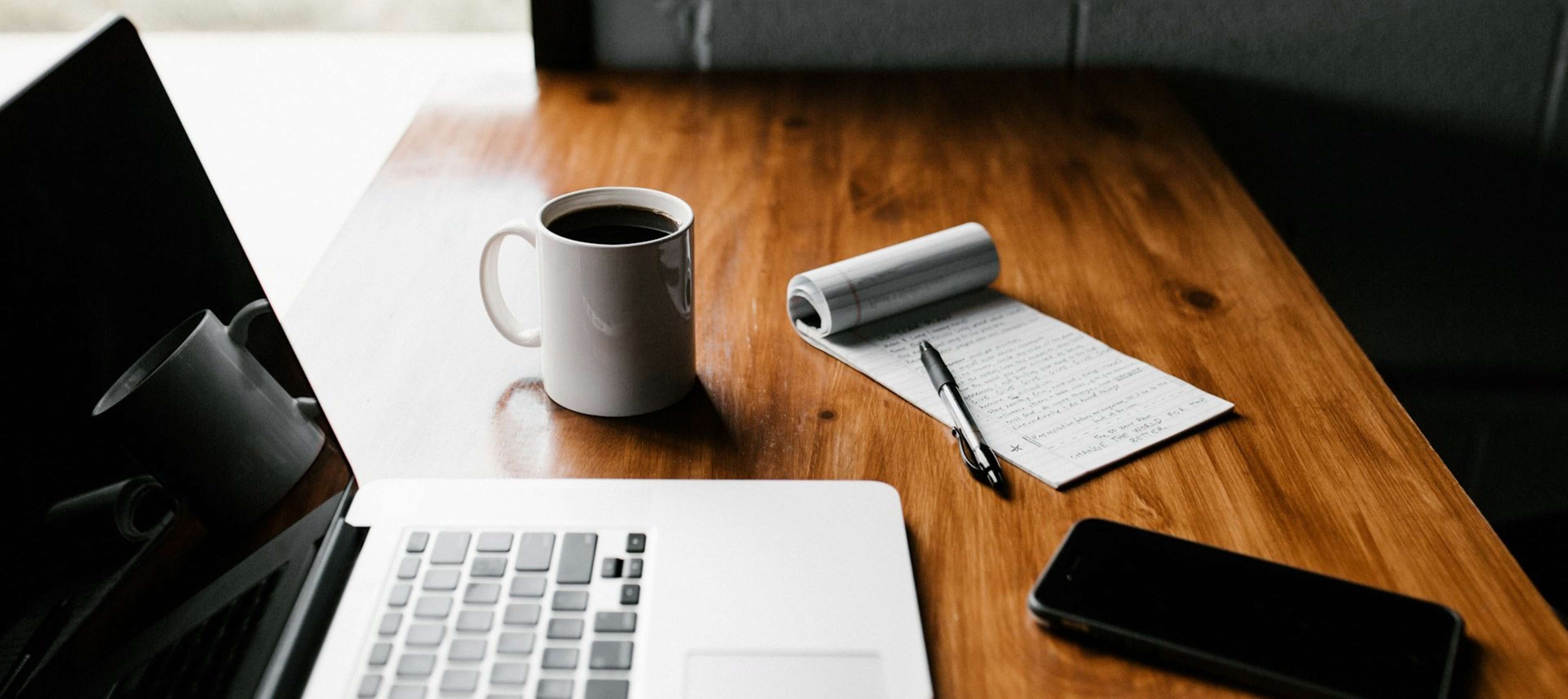 Work desk with a laptop, mug, notebook and pen